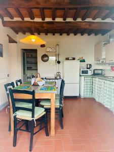 cocina con mesa, sillas y nevera en La casa In Valli 35, en Bagni di Lucca