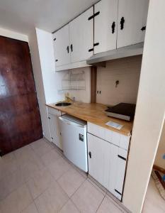 Una cocina con gabinetes blancos y una encimera de madera. en Estudio Brendel a metros del Centro Cívico, en San Carlos de Bariloche