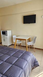 Un dormitorio con una cama, una mesa y un televisor. en Estudio Brendel a metros del Centro Cívico, en San Carlos de Bariloche