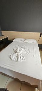 una cama blanca con una flor pintada en ella en Hotel Itavera II, en Presidente Prudente