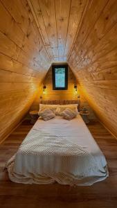 a large bed in a wooden room with a window at Casas da Madrinha in Arcos de Valdevez