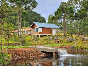 ein Haus am Ufer eines Sees mit einem Wasserfall in der Unterkunft Chalé do Lago Urupema SC in Urupema