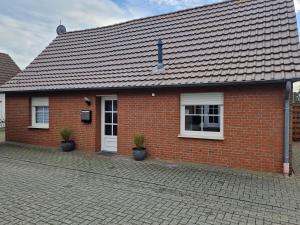 a red brick house with two potted plants in front of it at Ferienwohnungen Dümmersee - Haus Alter Pferdestall in Hüde