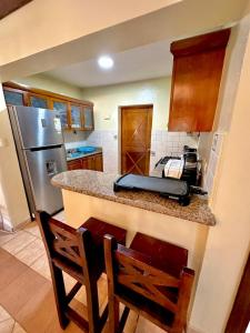 a kitchen with a counter with a refrigerator and chairs at Lujosa villa en Metro Country Club in La Puntica de Juan Dolio