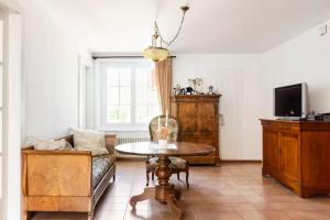 een woonkamer met een tafel en een bank bij Chambre d'hôte au milieu des vignes avec magnifique vue sur le lac et jardin in Féchy