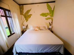 Un dormitorio con una cama blanca con plantas en la pared en Casa Tesoro Selva, en Tarapoto