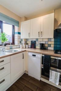 a kitchen with white cabinets and a sink at Spacious 1 bed flat-FREE Parking in New Bedfont