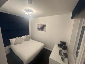a small bedroom with a white bed and a table at Luxe Hotel Blackpool in Blackpool