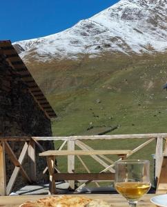 a glass of wine sitting on a table in front of a mountain at Guesthouse Ivas in Ushguli