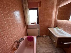 y baño con bañera rosa y lavamanos. en Spacious holiday home with sauna in Sauerland en Frankenau