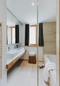 ein Bad mit einer Badewanne, einem Waschbecken und einer Dusche in der Unterkunft Arlberg Lodges in Stuben am Arlberg