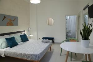 a white bedroom with a bed and a table at GUESTHOUSE GRANDI STAZIONI _ bari centro s.l._ in Bari