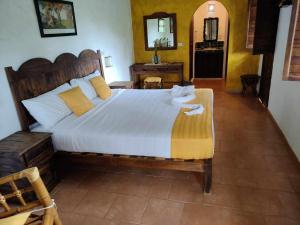 1 dormitorio con 1 cama grande con sábanas blancas y almohadas amarillas en Posada La Querencia, en Xico