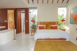 a bedroom with a white bed with orange and yellow pillows at Manao Villas in General Luna