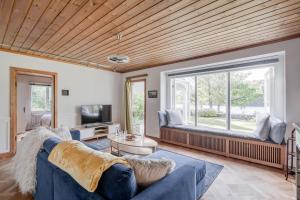 ein Wohnzimmer mit einem blauen Sofa und einem großen Fenster in der Unterkunft Large house by lake in Tollered in Tollered