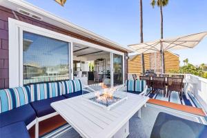 eine Terrasse mit Tisch, Stühlen und Sonnenschirm in der Unterkunft Stunning BayVIEW Home with Epic Waterfront Views! in Newport Beach