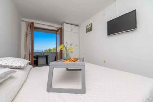 a white room with a table on a bed at Apartments in Veli Losinj 26474 in Veli Lošinj