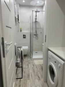 a bathroom with a shower and a washing machine at Apartament na Dworcowej Centrum in Wrocław