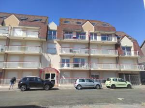a building with cars parked in front of it at L'Albatros 15 in Fort-Mahon-Plage