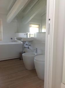 un bagno bianco con 2 lavandini e una vasca da bagno di Casa Selene Rocchi a Savignano sul Panaro