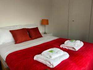 a bedroom with two towels on a red bed at Cosy 2 Bedroom House with Parking in Oxford in Kidlington