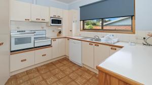 a kitchen with white cabinets and a window at Marlo at the Beach in Marlo