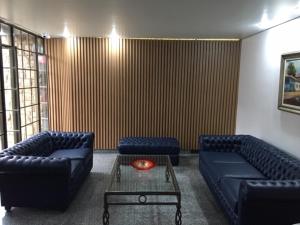 una sala de estar con 2 sofás azules y una mesa. en Fenix Hotel Pouso Alegre, en Pouso Alegre