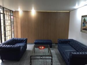 a living room with two blue couches and a table at Fenix Hotel Pouso Alegre in Pouso Alegre