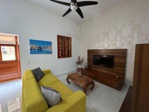 a living room with a yellow couch and a flat screen tv at Luxurious Sliema Ferry central location in Sliema
