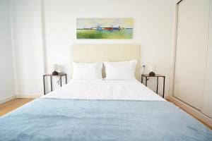 a bedroom with a large white bed with two tables at GALIHOST - Piso con parking en pleno centro de Cambados in Cambados