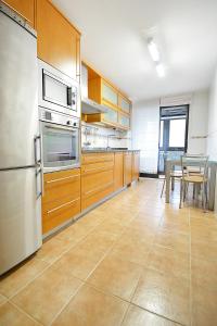 a kitchen with wooden cabinets and a table and a refrigerator at GALIHOST - Piso con parking en pleno centro de Cambados in Cambados