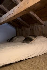ein Bett mit weißer Bettwäsche und Kissen unter einem Loft in der Unterkunft Stone Lake Luxury Lodge in Gérardmer