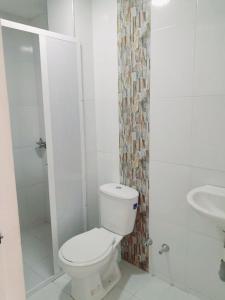 a white bathroom with a toilet and a sink at Apartahotel Cartagena in Cartagena de Indias