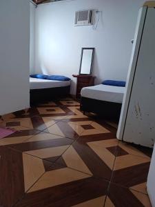 a room with two beds and a wooden floor at Pousada Aloha in Santos