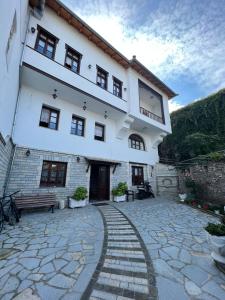 een groot wit gebouw met een bank ervoor bij Castle Hotel in Gjirokastër