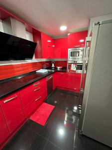 uma cozinha vermelha com armários vermelhos e um frigorífico em Jumeke Home em Castro-Urdiales