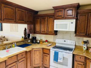 a kitchen with wooden cabinets and a white stove top oven at Brownsville Comfort 2 bedroom 1 bath , Spacious Kitchen and Outdoor Home in Brownsville