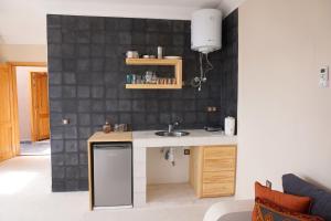 a kitchen with a sink and a black tiled wall at SurfAppart Morocco in Tamraght Ouzdar