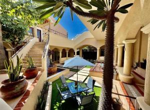 une maison avec un palmier, des chaises et un parasol dans l'établissement Marisol Hotel Boutique, à San José del Cabo