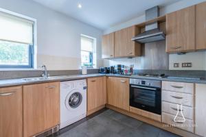 a kitchen with wooden cabinets and a washer and dryer at Luxury Birmingham City Centre Townhouse with BALCONY- Sleeps 10 - FREE Parking - Perfect for Contractors, Business Travellers, Families and other Groups - Near Bullring, Newstreet, Selfridges, NEC, NIA & Birmingham airport in Birmingham