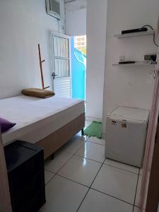 a small room with a bed and a small refrigerator at Pousada Aloha in Santos