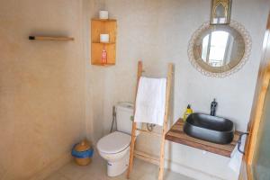 a bathroom with a toilet and a sink and a mirror at SurfAppart Morocco in Tamraght Ouzdar
