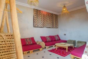 a living room with red couches and a table at SurfAppart Morocco in Tamraght Ouzdar