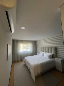 um quarto com uma cama branca e uma janela em Ap.Maria Bonita 