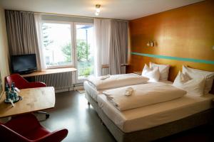 Habitación de hotel con 2 camas, escritorio y TV. en Abalon Hotel ideal en Stuttgart