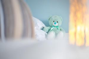 a teddy bear sitting on top of a bed at Gold Coast Photography Inn in Estoril