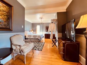 a living room with a television and a bed at Le Chateau du Lac in Magog-Orford