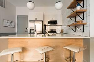 a white kitchen with two stools at a counter at Trendy Condo! Close to everthing Downtown in Birmingham