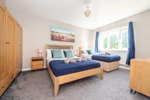 a bedroom with two beds and a window with blue curtains at Airport LPL - Driveway Parking - Garden in Widnes