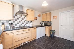 a kitchen with wooden cabinets and a stove top oven at Airport LPL - Driveway Parking - Garden in Widnes